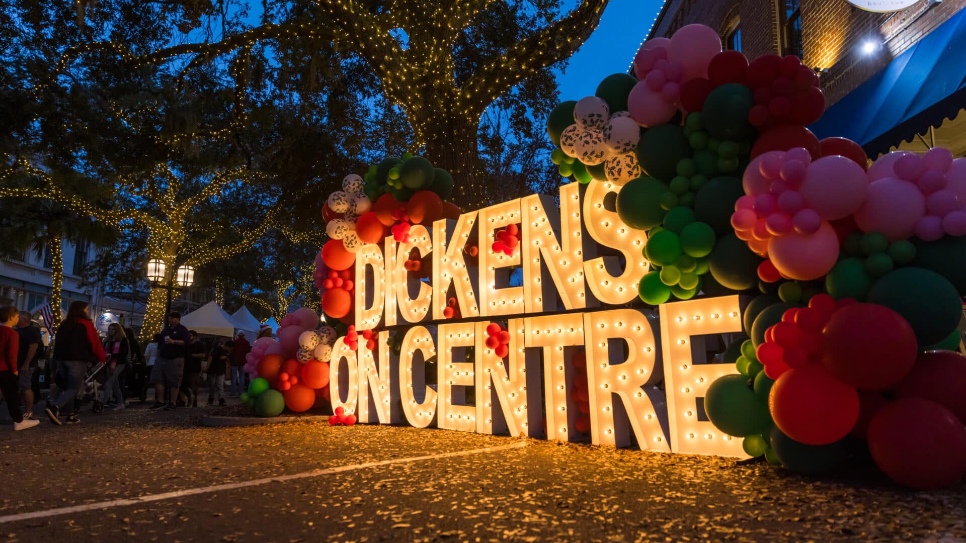 Lighted up letters spelling Dickens On Centre with balloons.