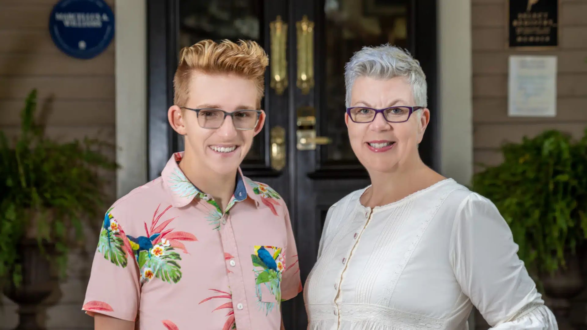 Person wearing pink shirt with blue birds and person wearing white shirt smiling at the camera