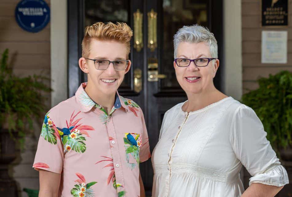 Person wearing pink shirt with blue birds and person wearing white shirt smiling at the camera