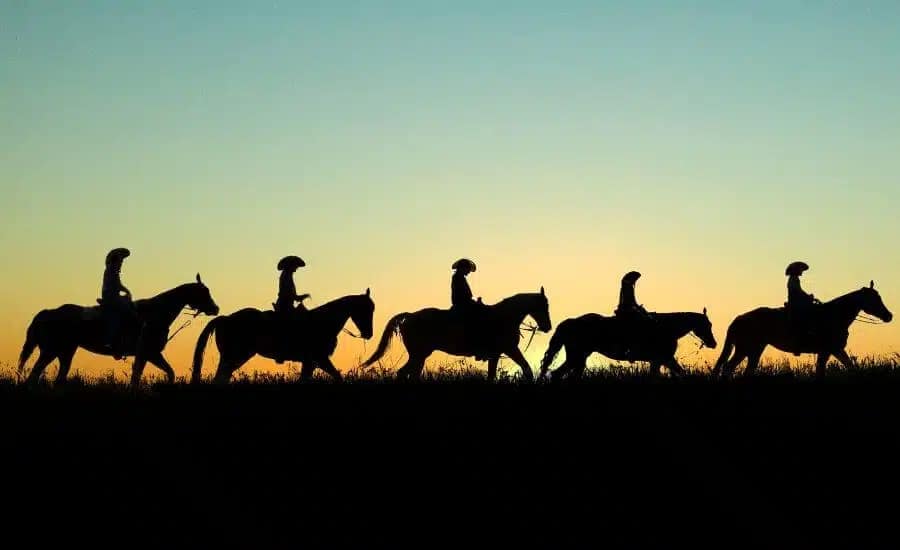 silhouette of a group of five people horseback riding at sunset