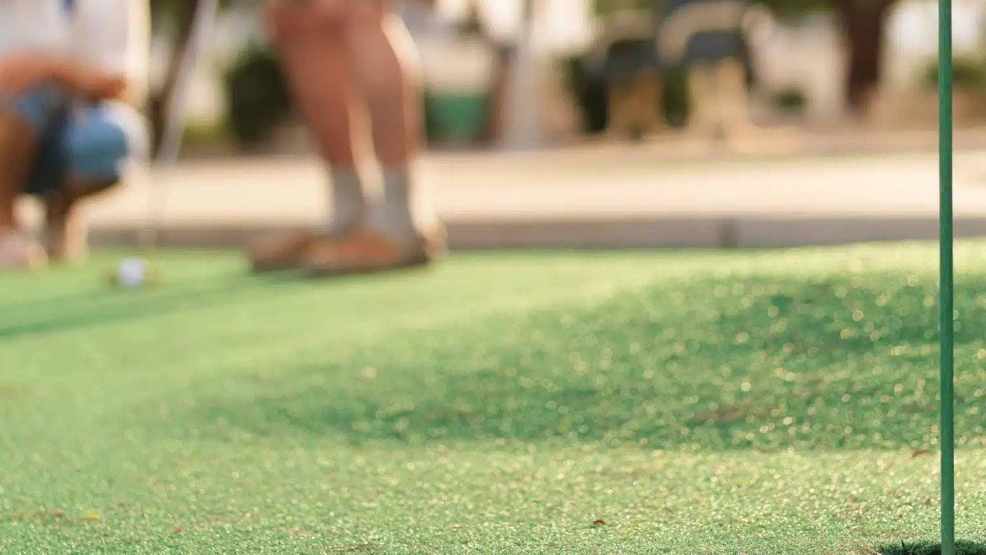 Close up view of hole on mini golf course with a blurred person in the background putting