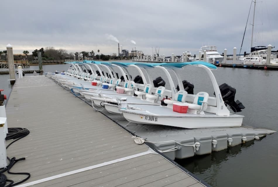 Many mini catamarans in a row docked at a harbor