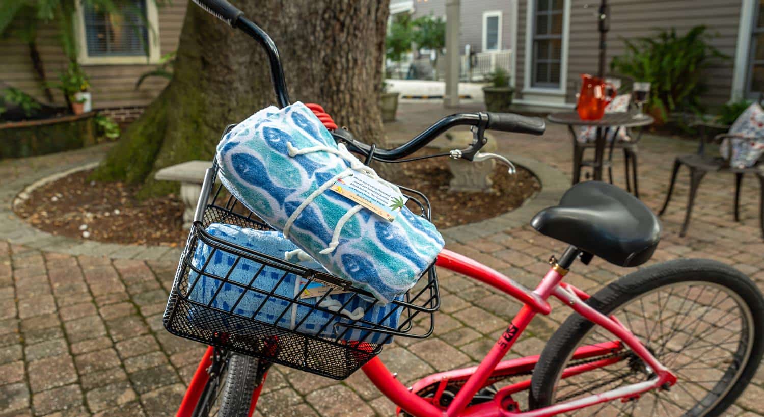 Close up view of red bike with a basket holding two rolled up beach towels