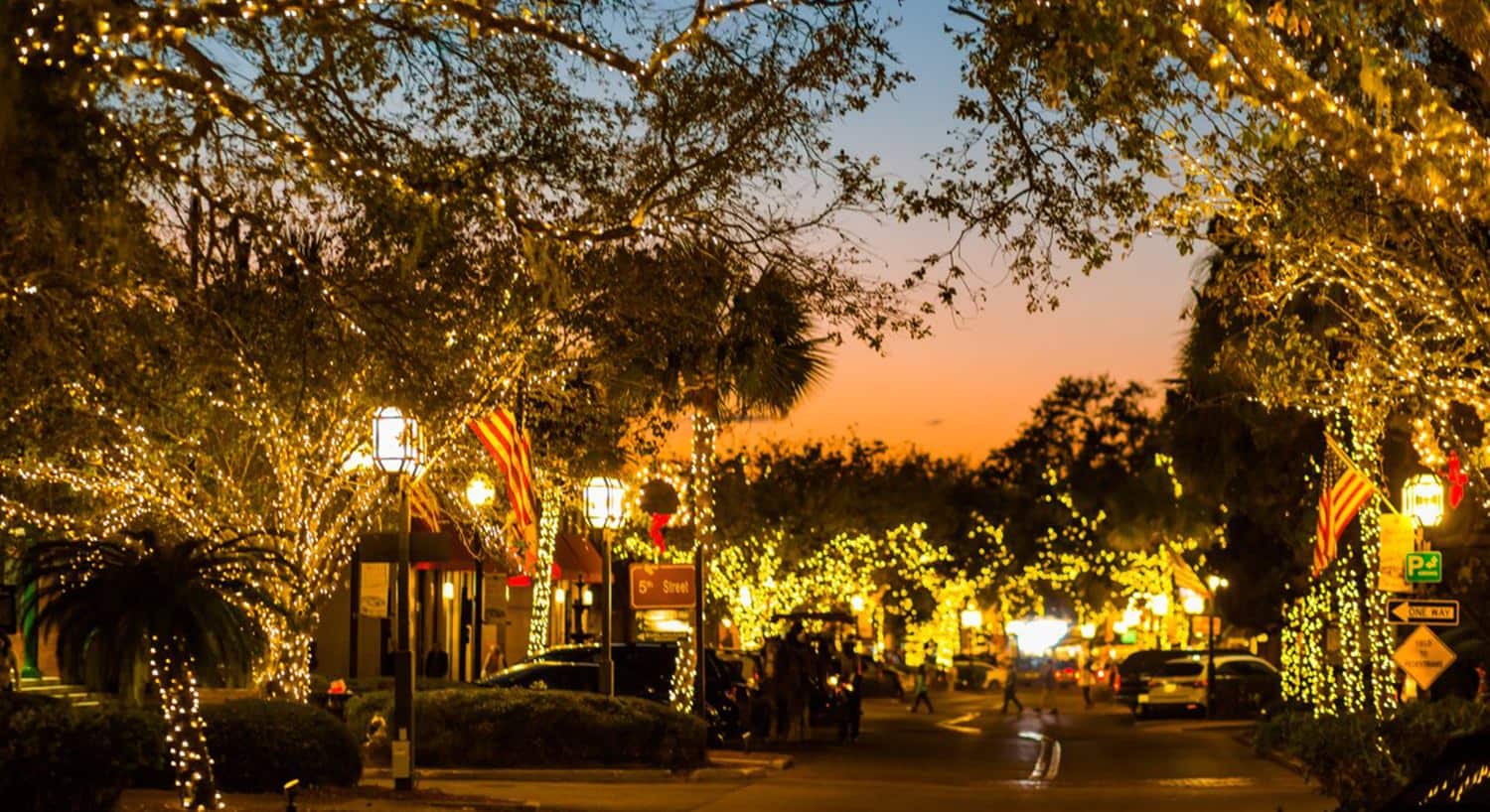 Small downtown street area at dusk lighted up with lights on all of the trees