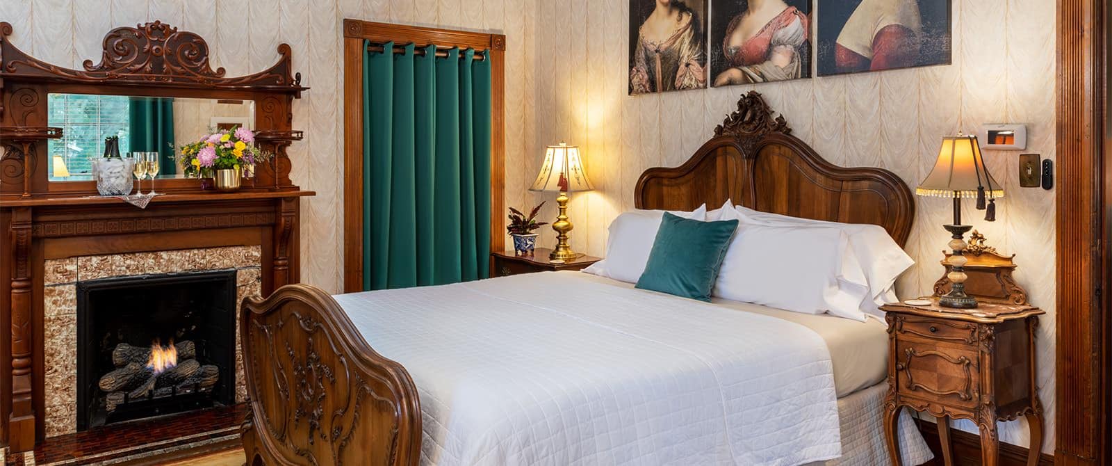 Bedroom with wallpaper, hardwood flooring, wooden bed, white bedding, white desk and chair, sitting area, and wooden dresser