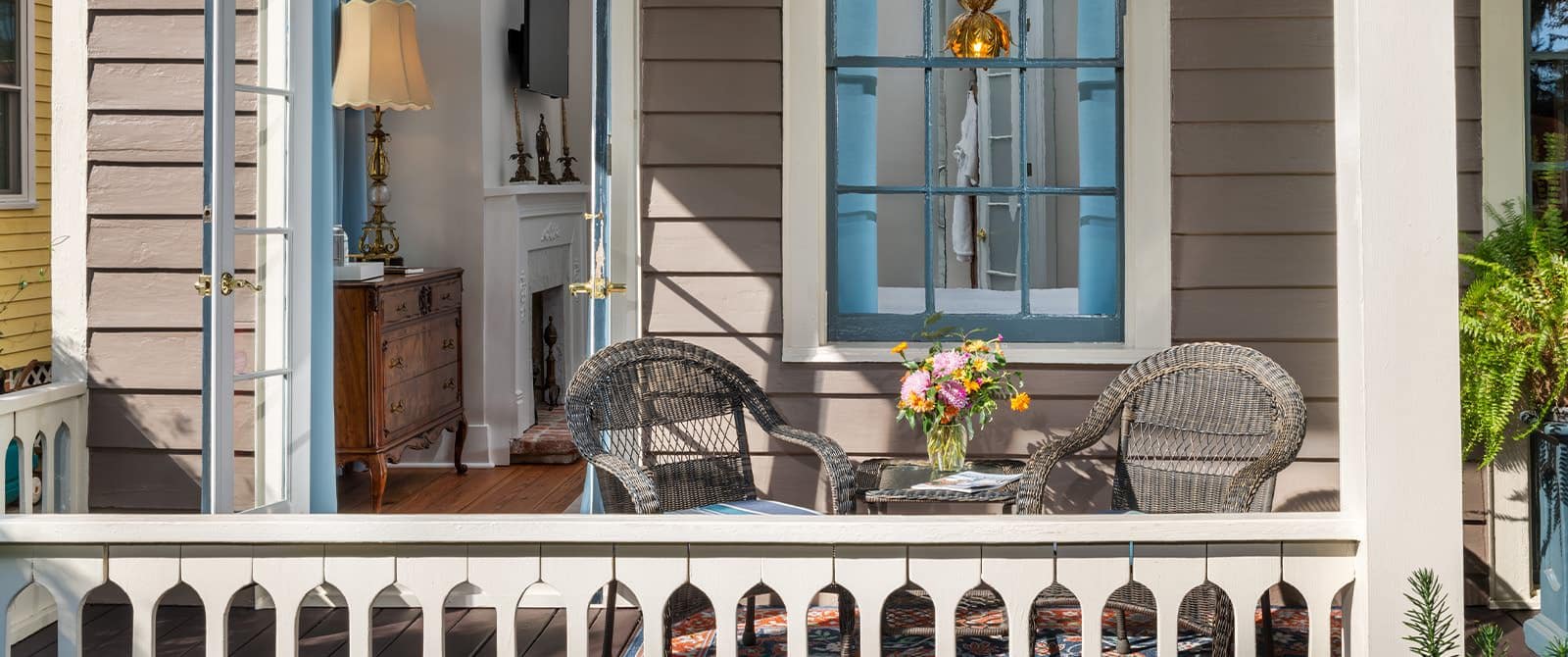 Balcony with wicker chairs and table, area rug, and potted plant