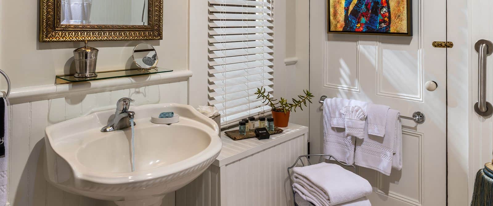 Bathroom with white walls, white sink, and gold framed mirror