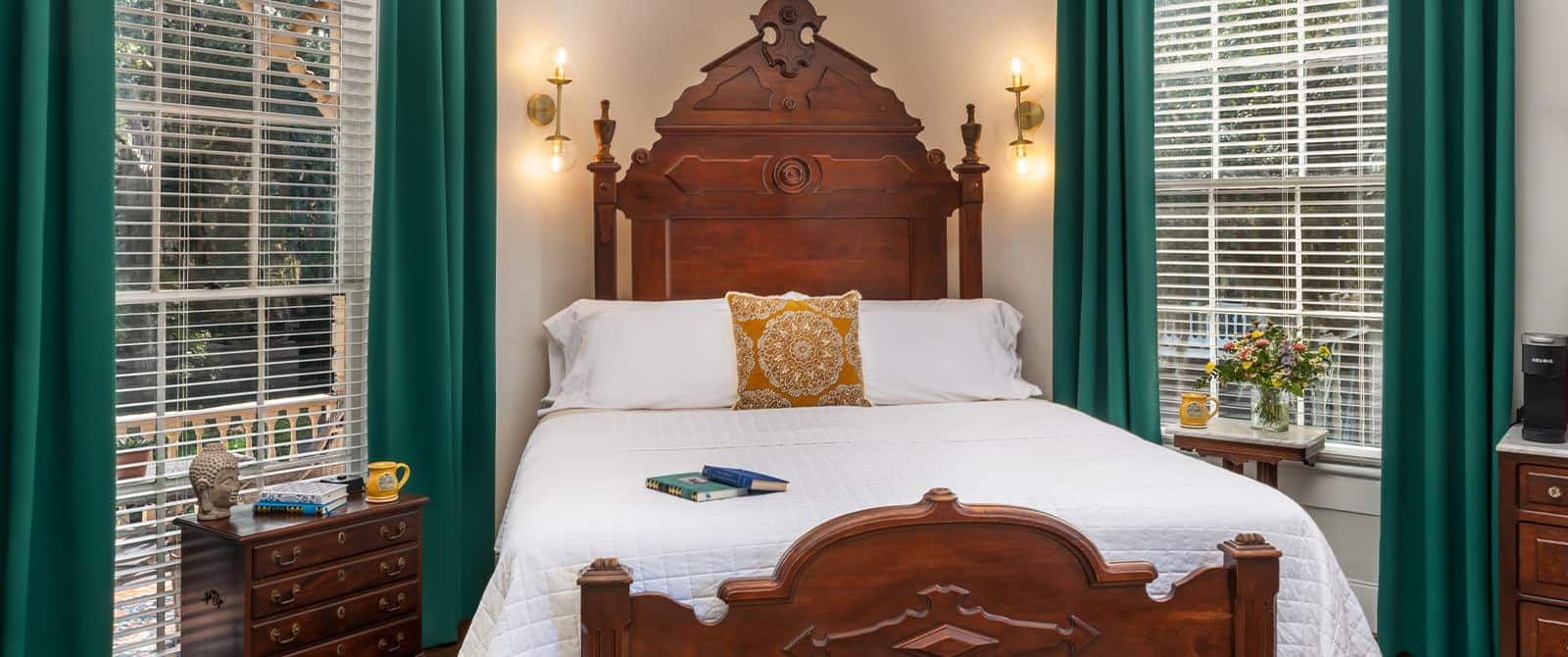 Bedroom with white walls, hardwood flooring, wooden headboard, white bedding, dark wooden dresser, and large windows