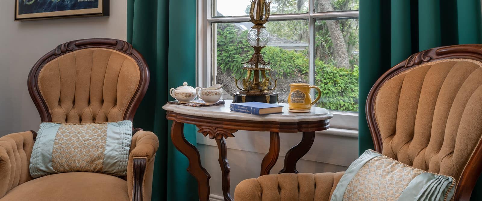 Close up of a bedroom's sitting area with antique armchairs and wooden table with marble top