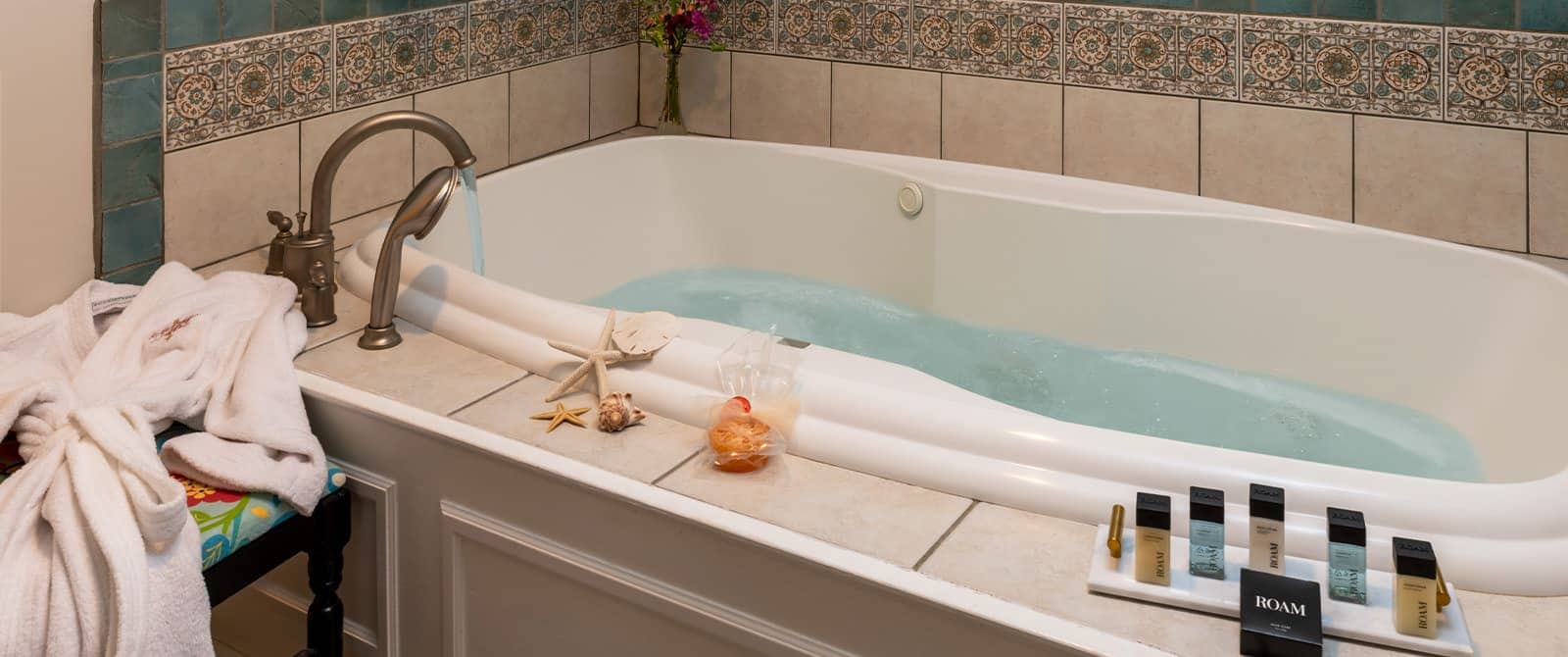 Close up view of jetted tub surrounded by light tan and blue tiles