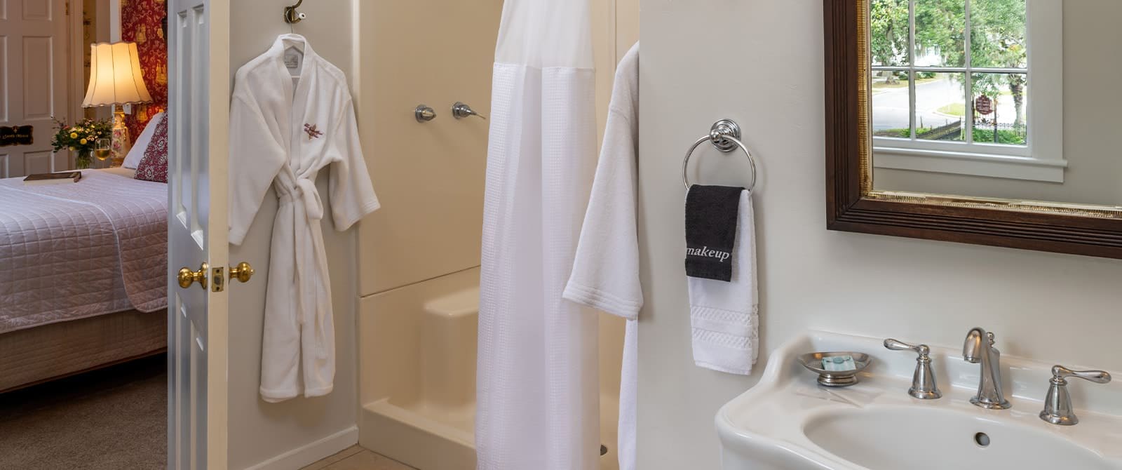 Bathroom with white walls, tiled flooring, stand up shower, white sink, and framed mirror