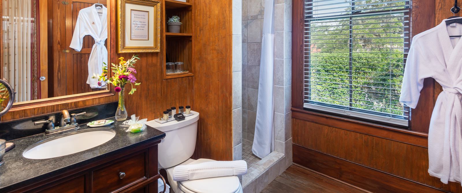 Bathroom with wooden paneling, hardwood flooring, tiled stand up shower, and dark wooden vanity