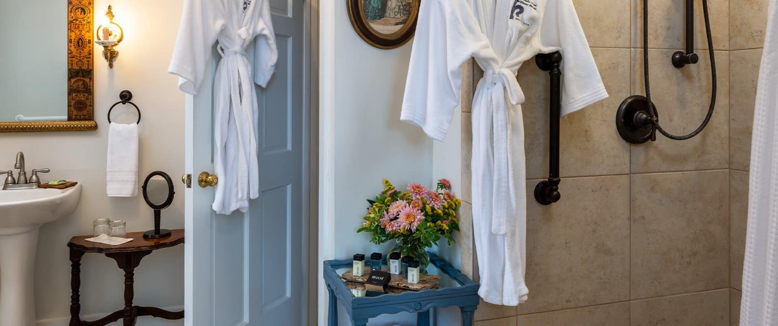 Bathroom with white walls, white sink, tiled shower, and ornate framed mirror