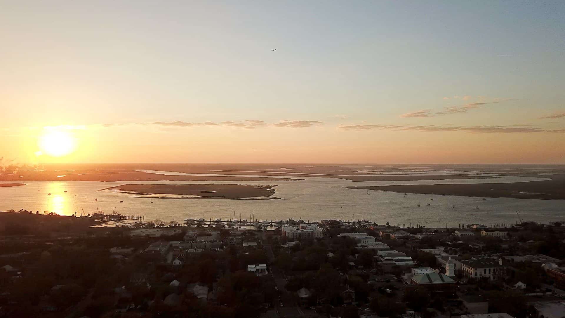 Aerial view of a town near the water with the sun setting in the background