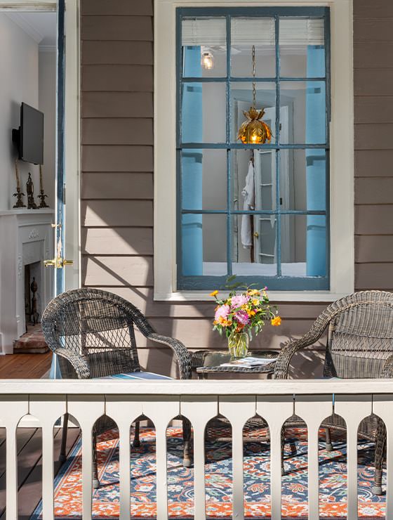 Close up view of exterior porch with dark wicker patio furniture and vase with pink and orange flowers