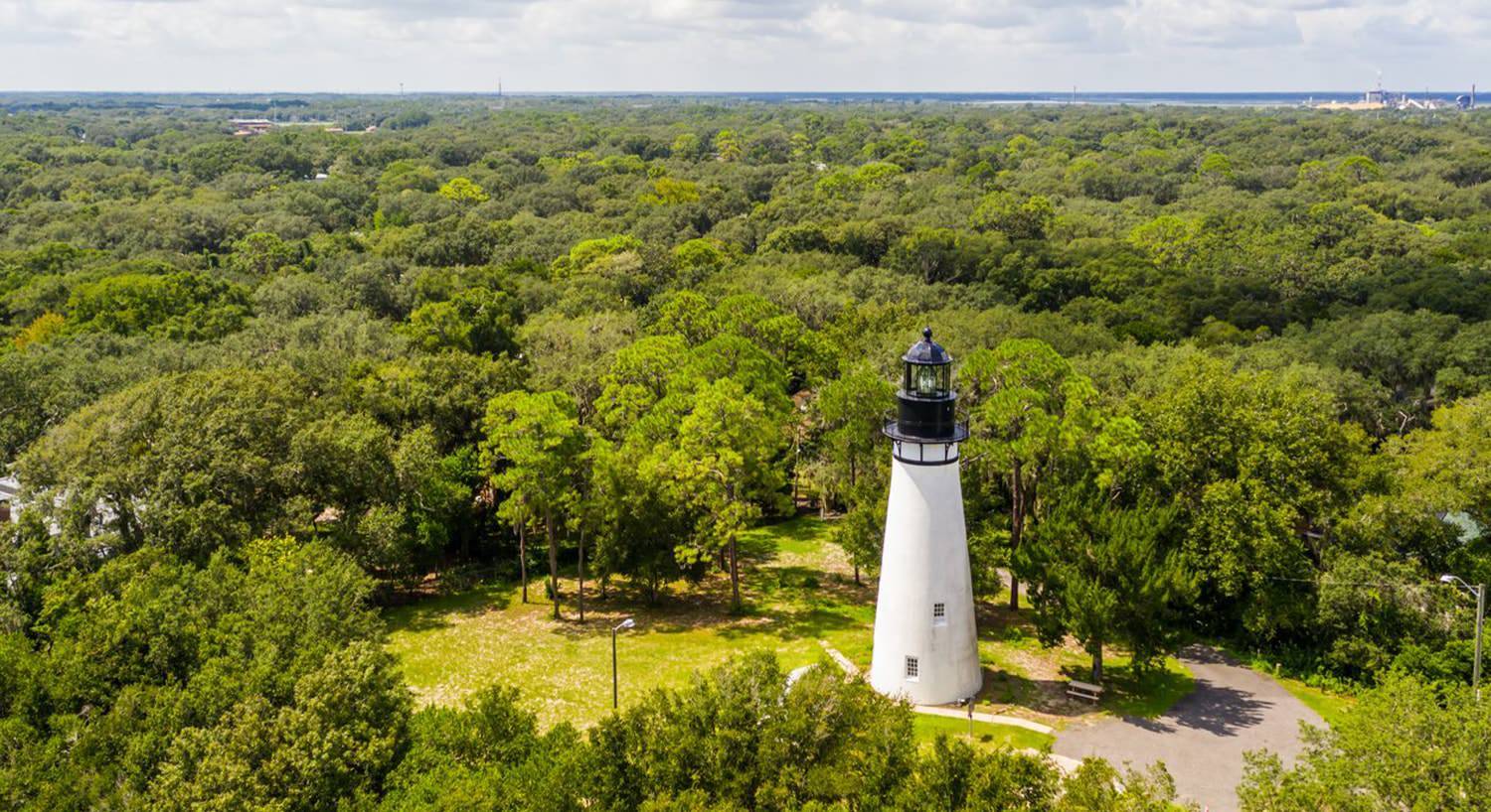 Aerial view of white lighthouse surrounded by green trees