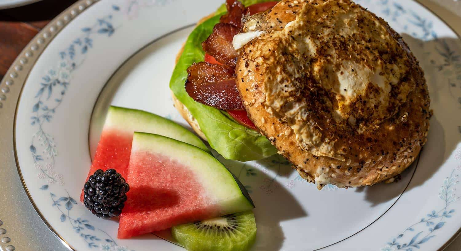 Close up view of breakfast sandwich with watermelon on fine porcelain china plates